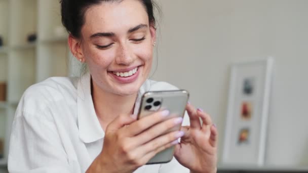 Seorang Wanita Cantik Mengirimkan Pesan Menggunakan Smartphone Sambil Tersenyum Berbaring — Stok Video
