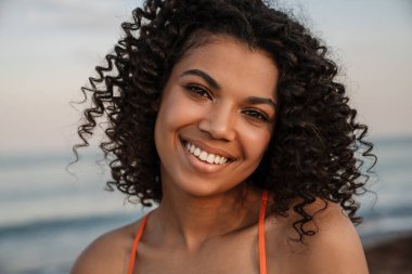 Sahilde yürüyen güzel, mutlu, Afrikalı bir kadın.