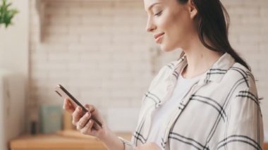 Evde cep telefonu kullanan neşeli hamile esmer kadın.