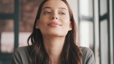 Gülümseyen genç bayan evde, mutfakta oturuyor.