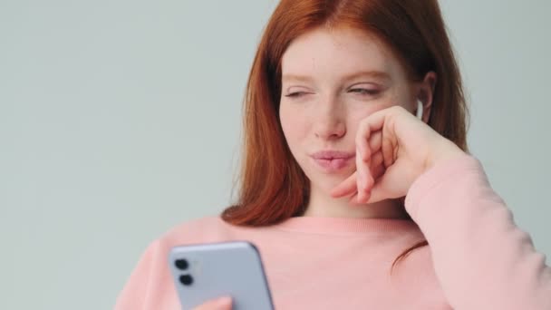 Giovane Rossa Pensando Ragazza Utilizzando Telefono Cellulare Auricolari Isolati Sfondo — Video Stock