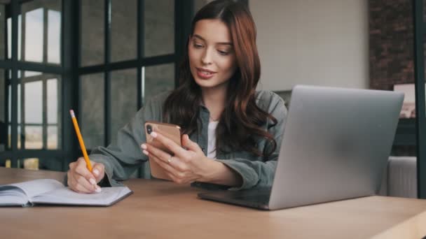 Mujer Joven Feliz Usando Teléfono Móvil Ordenador Portátil Mientras Escribe — Vídeos de Stock