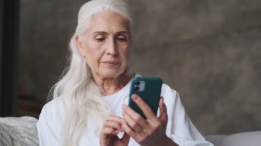 Evde cep telefonu kullanan son sınıf öğrencisi bir kadın.
