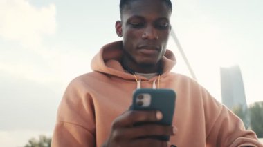 Odaklanmış bir Afrikalı Amerikalı 'nın yakından görüntüsü, köprüde dururken akıllı telefonundan bir şey izliyor.