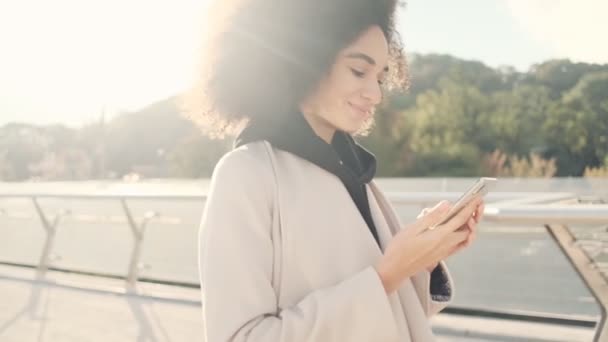 Potěšená Americká Žena Používá Svůj Smartphone Při Chůzi Mostě — Stock video