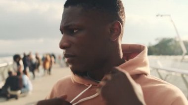 Ciddi bir Afro-Amerikan adamının yakından görüntüsü köprünün dışında yürürken bir başlık takıyor.