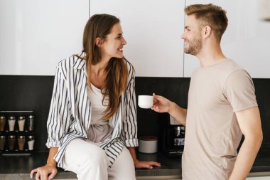 Kafkasyalı güzel bir çift evde gülümseyip kahve içiyorlar.