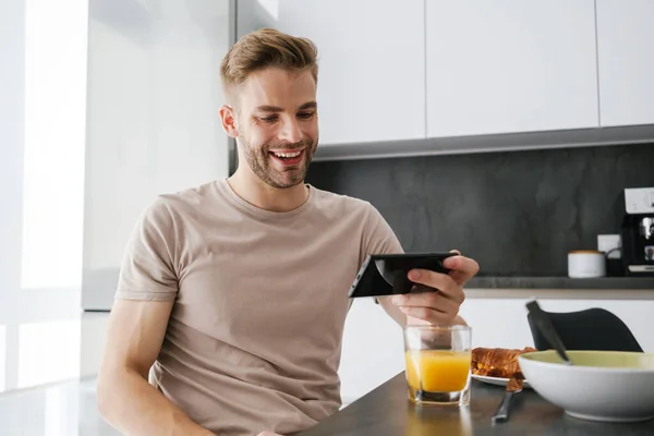 Young Handsome Caucasian Man Holding Cellphone While Having Breakfast Home — Stock Photo, Image