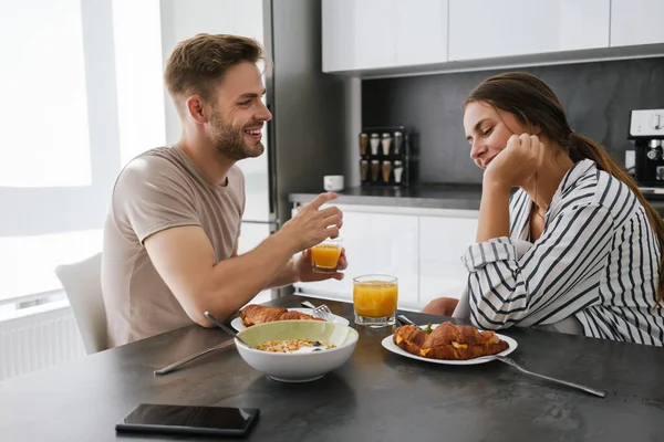 stock image Young beautiful caucasian couple sitting at table while having breakfast at home