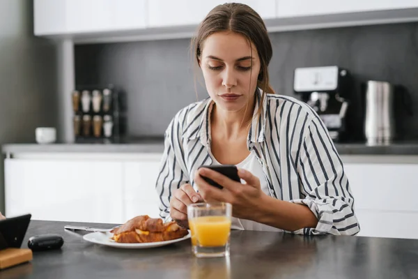 Fiatal Fehér Kezében Mobiltelefon Miközben Otthon Reggelizik — Stock Fotó