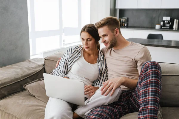 Joven Pareja Hermosa Caucásica Sentado Sofá Casa Celebración Computadora Portátil —  Fotos de Stock