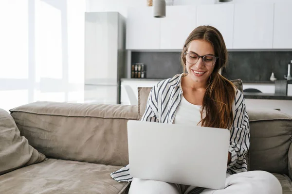 Jovem Caucasiana Feliz Mulher Sorrindo Usando Laptop Enquanto Sentado Sofá — Fotografia de Stock