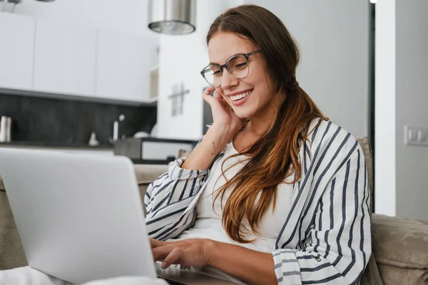 Jovem Caucasiana Feliz Mulher Sorrindo Usando Laptop Enquanto Sentado Sofá — Fotografia de Stock