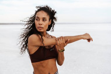 Atletik Afro-Amerikan sporcu kadının doğa üzerinde çalışırken egzersiz yapması.