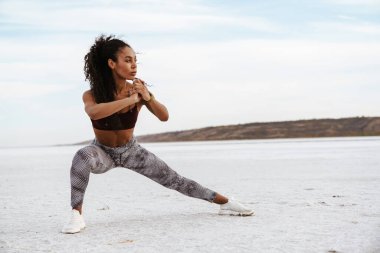 Kendine güvenen genç Afrikalı kadın tuz gölünde esneme egzersizleri yapıyor.