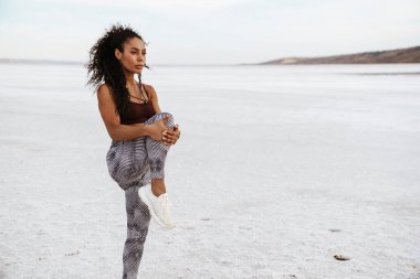 Atletik Afro-Amerikan sporcu kadının doğa üzerinde çalışırken egzersiz yapması.