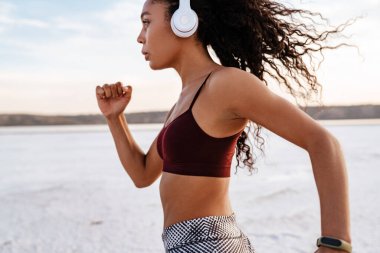 Doğada spor yaparken kulaklıklı Afro-Amerikan sporcu kadının görüntüsü
