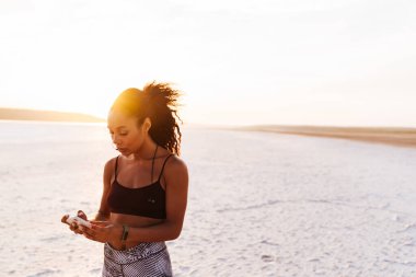 Afrika kökenli Amerikalı sporcunun doğa üzerinde çalışırken kulaklık ve cep telefonu kullanması.