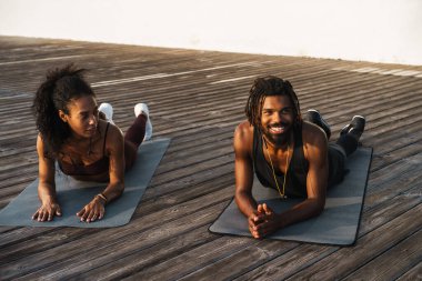 Genç, güzel, mutlu, Afro-Amerikan erkek ve kadın dışarıda egzersiz yapıyorlar.