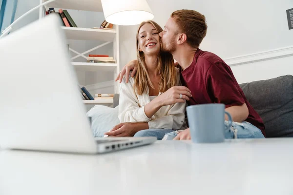 Imagen Jengibre Alegre Pareja Besándose Usando Ordenador Portátil Mientras Está — Foto de Stock