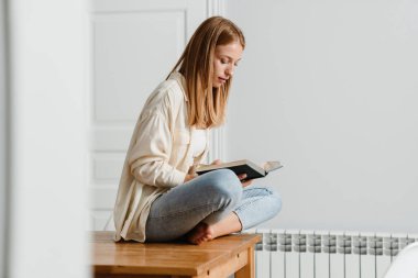 Evde masada otururken kızıl odaklı kitap okuyan kız görüntüsü