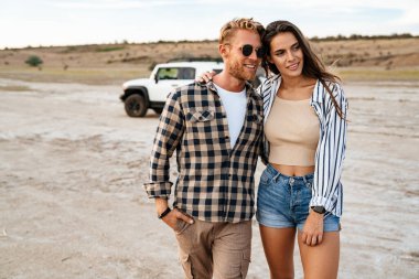 Kumsalda, arabada yürürken, kucaklaşırken genç ve mutlu bir çift.