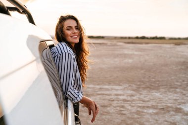 Kumsalın penceresinden dışarı bakan mutlu ve çekici genç bir kadın.