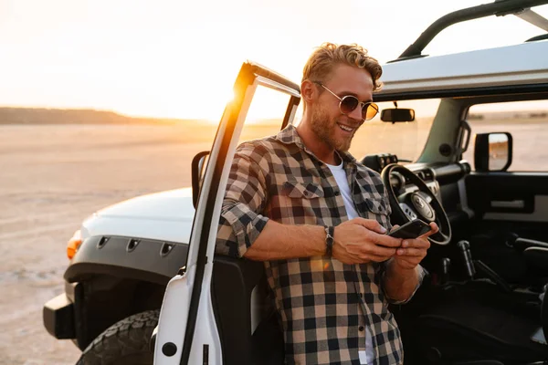 Knappe Jongeman Met Behulp Van Mobiele Telefoon Terwijl Hij Bij — Stockfoto