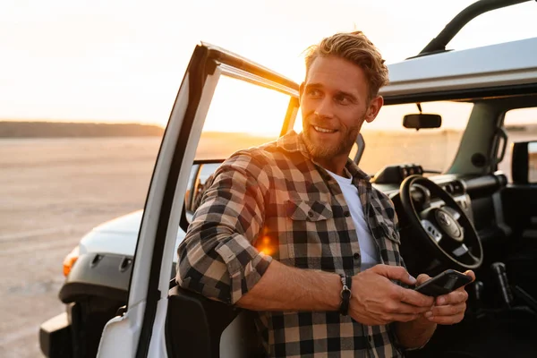 Knappe Jongeman Met Behulp Van Mobiele Telefoon Terwijl Hij Bij — Stockfoto