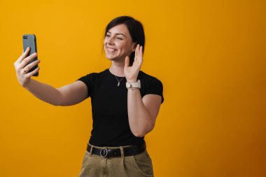 Sarıda izole edilmiş selfie çeken güzel bir genç kadının portresi.