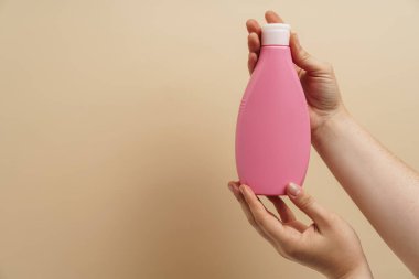 Kadının ellerinde losyon şişesi görünüyor.