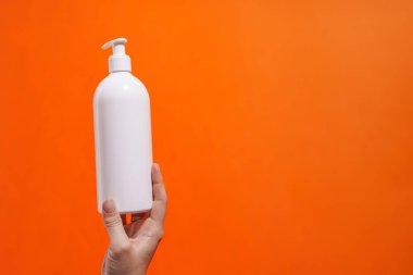 Kadının elinde boş losyon şişesi görünüyor.