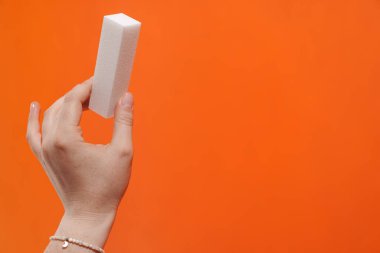 Kadının eli arka planda izole edilmiş tırnak törpüsü gösteriyor