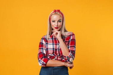 Sarı arka planda izole edilmiş, gülümseyen ve göz kırpan neşeli sarışın poster kızı görüntüsü