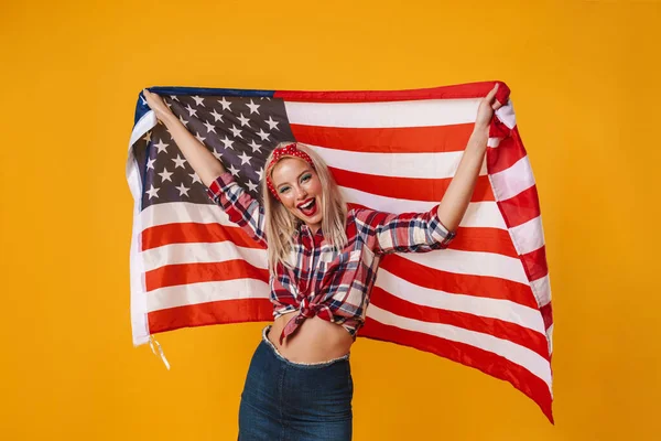 照片中快乐迷人的女孩举着美国国旗 在黄色的背景下面带微笑 — 图库照片