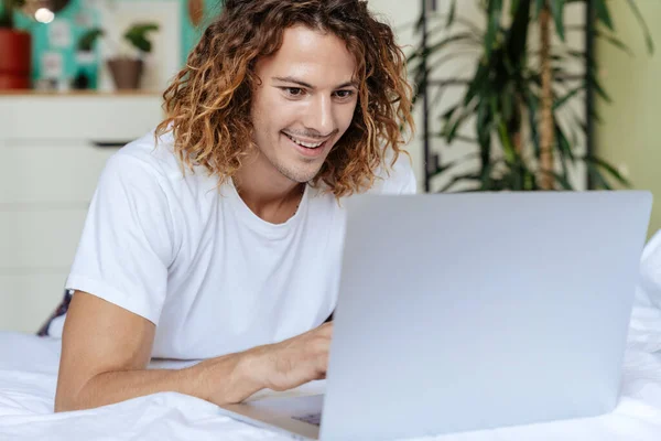 白人ハンサムな幸せな男使用してノートパソコン中にベッドで自宅 — ストック写真