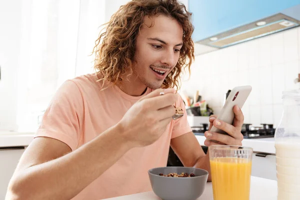Caucasian Handsome Smiling Guy Using Cellphone While Having Breakfast Kitchen — Stock Photo, Image