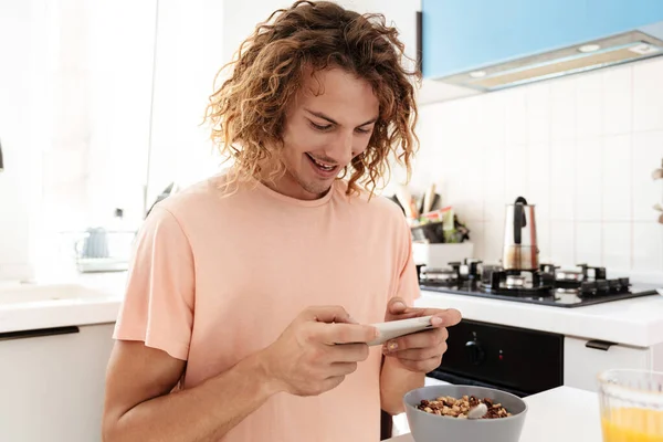 Caucasian Smiling Guy Playing Online Game Cellphone While Having Breakfast — Stock Photo, Image