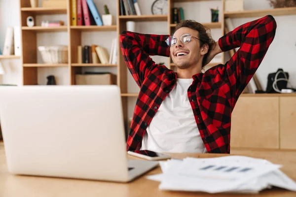 Красивий Усміхнений Хлопець Окулярах Працює Ноутбуком Сидячи Офісі — стокове фото