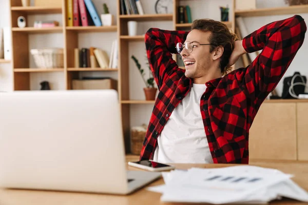 사무실에 안경을 잘생긴 미소짓는 남자가 노트북으로 작업하는 — 스톡 사진