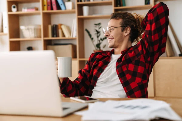 Guapo Sonriente Chico Gafas Bebiendo Café Mientras Trabaja Con Ordenador — Foto de Stock