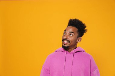 Neşeli Afro-Amerikalı adam gülümsüyor ve sarı arka planda yalnız başına bakıyor.