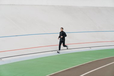 Stadyumda koşan kendinden emin genç bir sporcu.