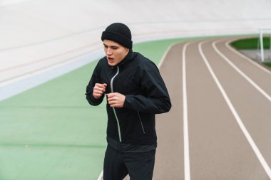 Stadyumda koşmadan önce kendine güvenen genç adam ısınıyor.