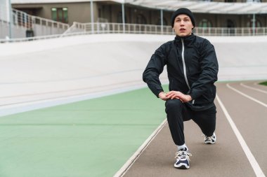 Stadyumda koşmadan önce kendine güvenen genç adam ısınıyor.