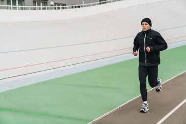 Stadyumda spor yaparken koşan yakışıklı sporcu.