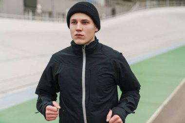 Stadyumda spor yaparken koşan yakışıklı sporcu.