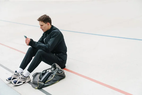 Desportista Jovem Atraente Usando Telefone Celular Enquanto Sentado Estádio Descansando — Fotografia de Stock