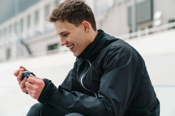 Bonito Desportista Feliz Usando Telefone Celular Enquanto Sentado Estádio Livre — Fotografia de Stock