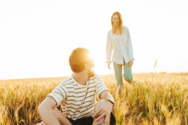 Sahada oturup kız arkadaşını bekleyen yakışıklı bir genç resmi.